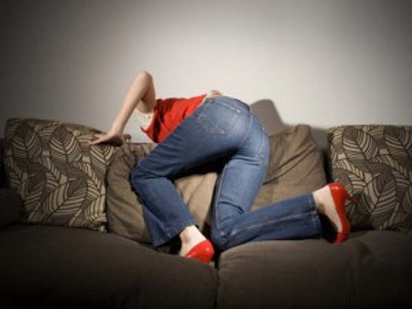 A girl bent over a couch going after the things she lost